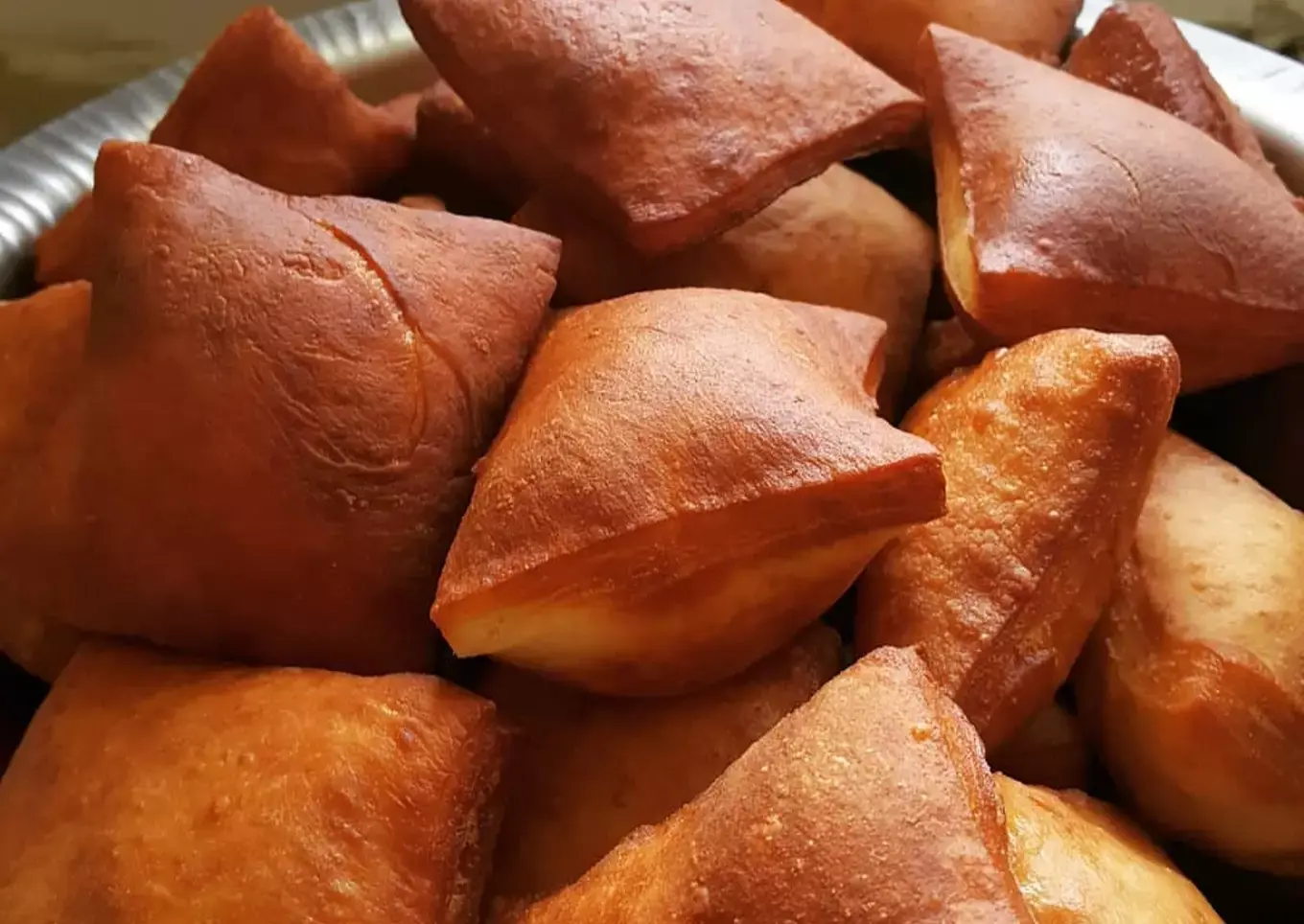 Stack of golden East African mandazi on parchment paper